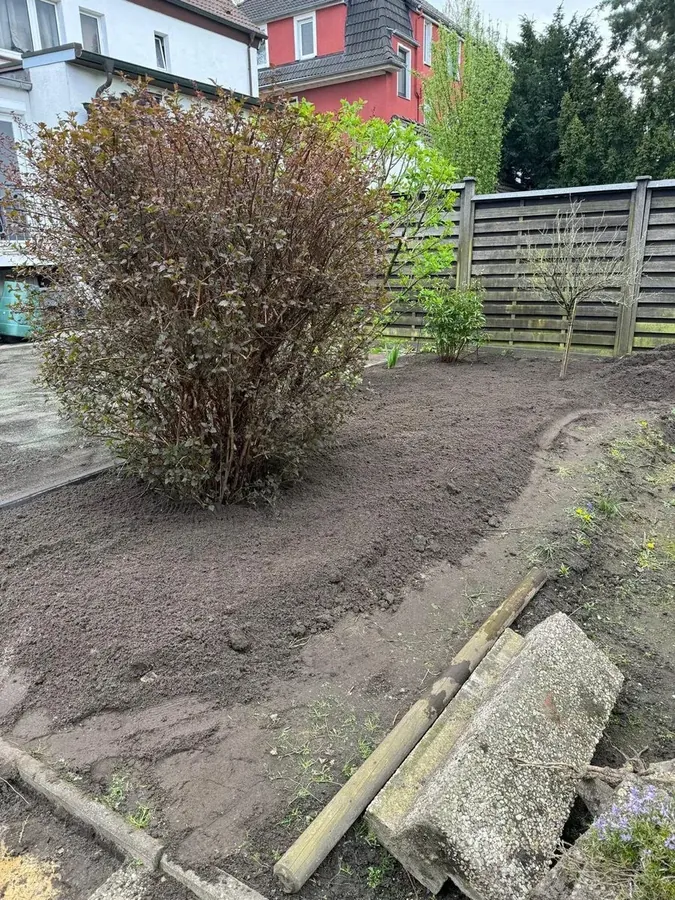 Garten vor dem Terrassenbau: das Erdreich ist abgetragen und planiert, im Hintergrund der Sichtschutzzaun